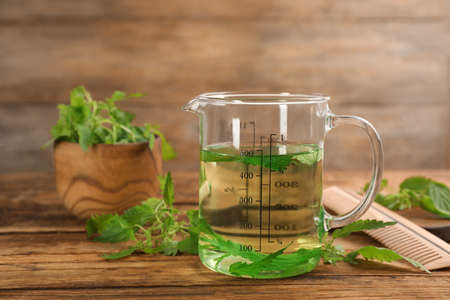 Stinging nettle extract and leaves on wooden background. Natural hair careの写真素材