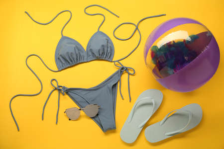 Stylish blue bikini and beach accessories on yellow background, flat layの写真素材