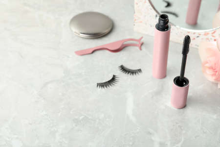 Mascara, fake eyelashes and tweezers on light table, space for text. Makeup productの写真素材