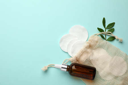 Cotton pads, leaf and makeup removal product on light blue background, flat lay. Space for textの写真素材
