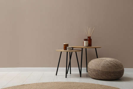 Knitted pouf and decor elements near beige wall indoors. Space for textの写真素材