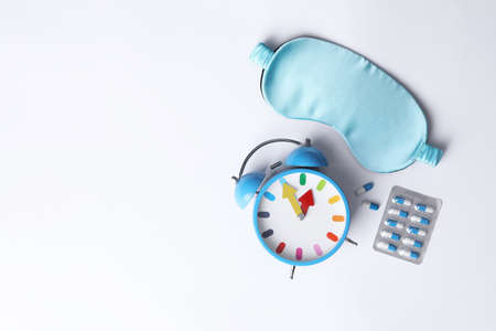 Sleeping mask, pills and alarm clock on white background, flat lay. Insomnia treatmentの写真素材