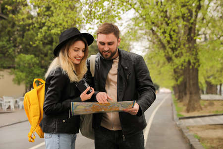 Couple of tourists with map planning trip on city street