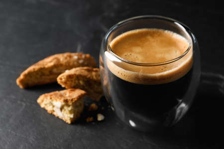 Tasty cantucci and cup of aromatic coffee on black table, closeup. Traditional Italian almond...