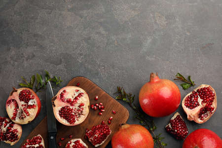 Delicious ripe pomegranates on gray table, flat lay. Space for textの写真素材