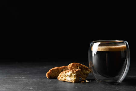 Tasty cantucci and cup of aromatic coffee on black table, space for text. Traditional Italian almond biscuitsの写真素材