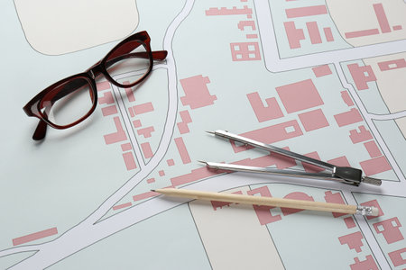 Office stationery and eyeglasses on cadastral map of territory with buildings