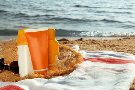 Sun protection products and beach accessories on blanket near sea, space for textの写真素材