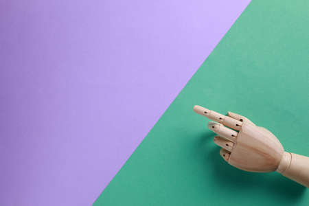 Wooden mannequin hand on color background, top view. Space for text
