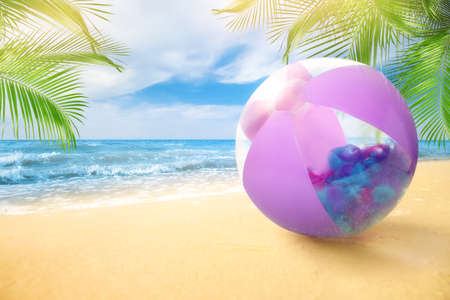 Violet beach ball on sandy coast near sea, space for textの写真素材