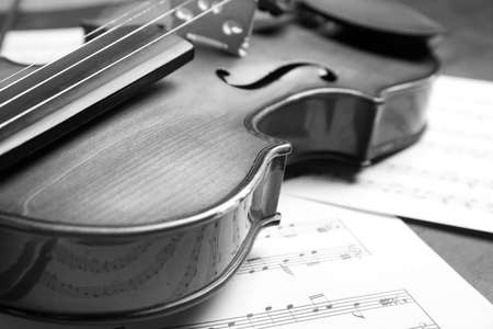 Beautiful violin and note sheets on table, closeup. Black and white toneの写真素材