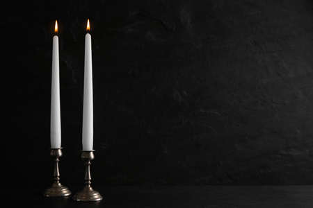 Elegant candlesticks with burning candles on black table. Space for textの写真素材