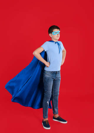 Teenage boy in superhero costume on red backgroundの写真素材