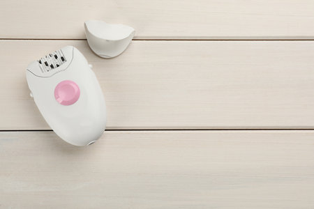 Modern epilator and cap on white wooden table, flat lay. Space for textの写真素材