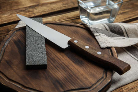 Sharpening stone and knife on wooden board, closeupの写真素材