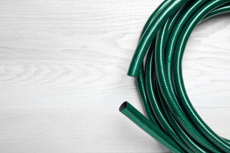 Green garden hose on white wooden table, top view. Space for textの写真素材