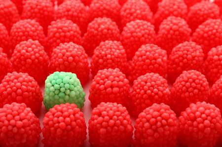 Delicious green gummy raspberry candy among red ones on pink backgroundの写真素材