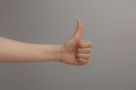 Woman showing thumb up on gray background, closeupの写真素材