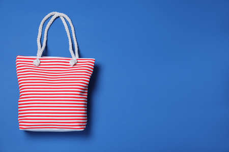 Stylish striped beach bag on blue background, top view. Space for text