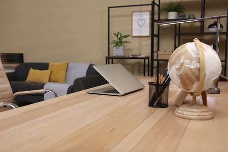 Comfortable workplace with laptop on wooden table in room. Interior design