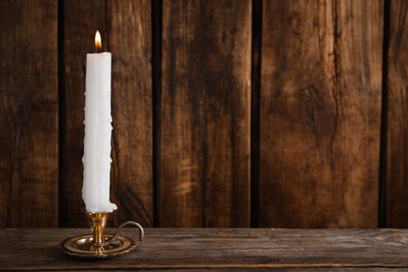 Elegant candlestick with burning candle on wooden table. Space for textの写真素材