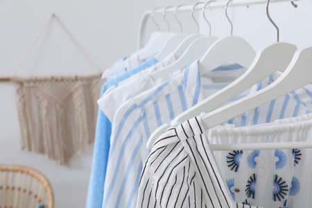 Rack with stylish hanging clothes in dressing room