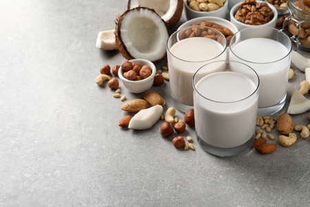 Vegan milk and different nuts on gray table