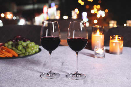 Glasses of red wine on table against blurred cityscape. Modern outdoor terrace