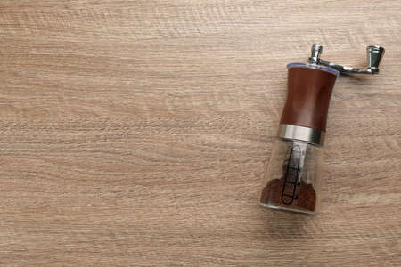 Modern manual coffee grinder on wooden table, top view. Space for textの写真素材