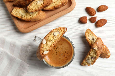 Tasty cantucci, cup of aromatic coffee and nuts on white wooden table, flat lay. Traditional Italian almond biscuitsの写真素材