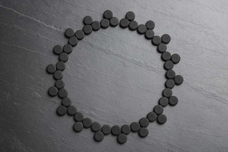 Frame of activated charcoal pills on black table, flat lay with space for text. Potent sorbentの写真素材