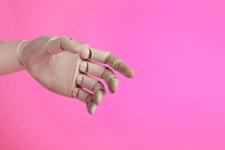Wooden mannequin hand on pink background. Space for textの写真素材