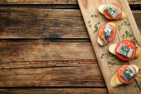 Delicious sandwiches with salted herring, tomatoes and thyme on wooden table, top view. Space for textの写真素材