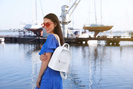 Beautiful young woman with stylish backpack near riverの写真素材