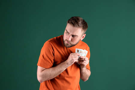 Greedy young man hiding money on green backgroundの写真素材