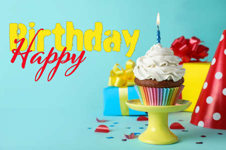 Happy Birthday! Delicious cupcake with burning candle on light blue backgroundの写真素材