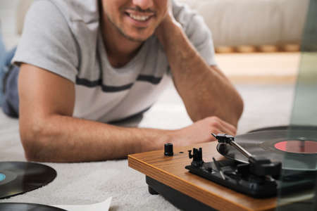 Happy man using turntable at home, closeup