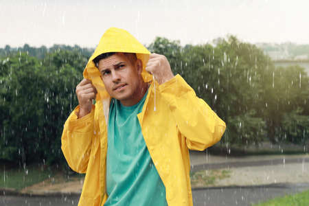 Man with raincoat walking under rain in parkの写真素材