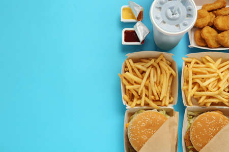 Different fast food on turquoise background, flat lay. Space for textの写真素材