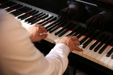 Man playing grand piano, closeup. Talented musician