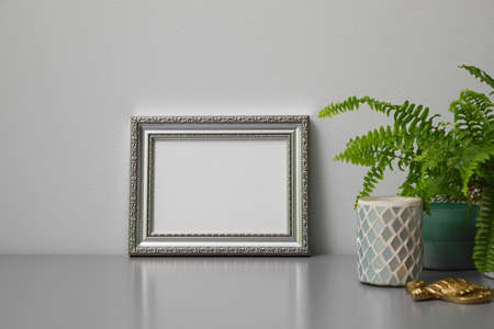 Empty photo frame, candles and green plant on gray tableの写真素材