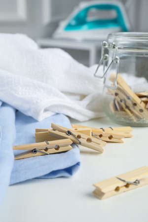 Many wooden clothespins and garments on white table indoorsの写真素材