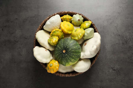 Fresh ripe pattypan squashes in wicker bowl on gray table, top viewの写真素材