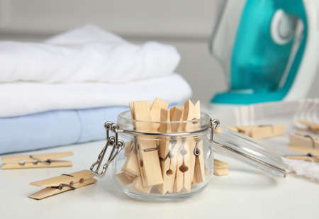Many wooden clothespins and glass jar on white tableの写真素材