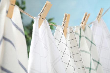 Washing line with wooden clothespins and fabrics against blurred backgroundの写真素材