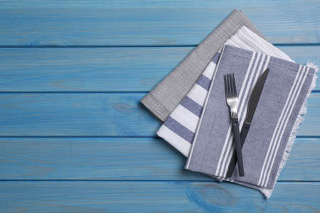 Different kitchen towels with cutlery on blue wooden table. Space for textの写真素材