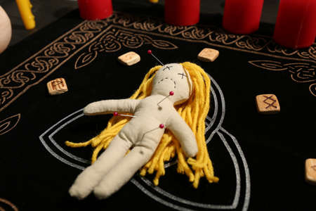 Voodoo doll pierced with pins and runes on black mat. Curse ceremonyの写真素材