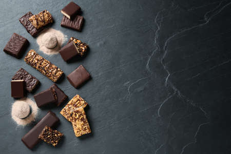 Different tasty energy bars and protein powder on black table, flat lay. Space for textの写真素材