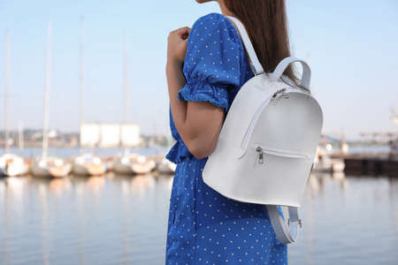 Young woman with stylish backpack near river, closeup