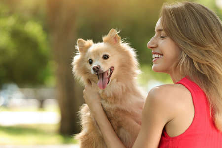 Young woman with her cute dog in park, space for textの写真素材